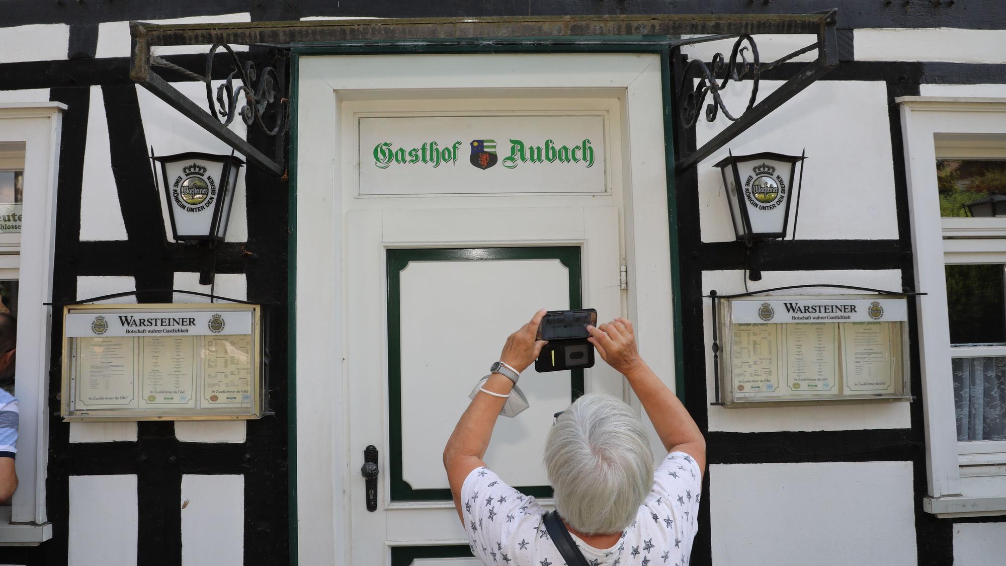 Eine Frau fotografiert den Schriftzug über der Tür des TV-„Gasthof Aubach“ in Kürten-Olpe.