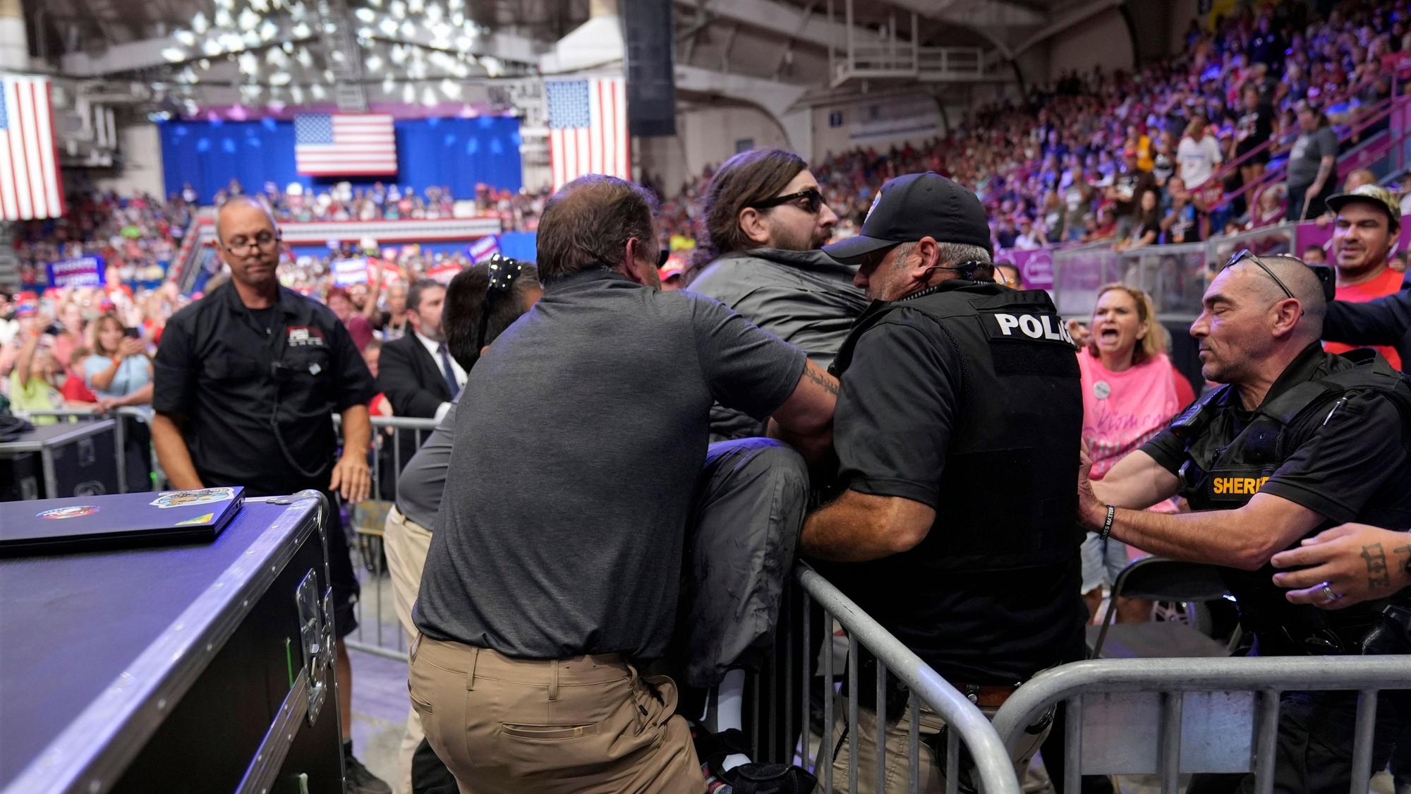 Die Polizei entfernt einen Mann (Mitte), der auf das Podium geklettert ist, als der republikanische US-Präsidentschaftskandidat und ehemalige US-Präsident Trump auf einer Wahlkampfveranstaltung in Johnstown, Pennsylvania, spricht.