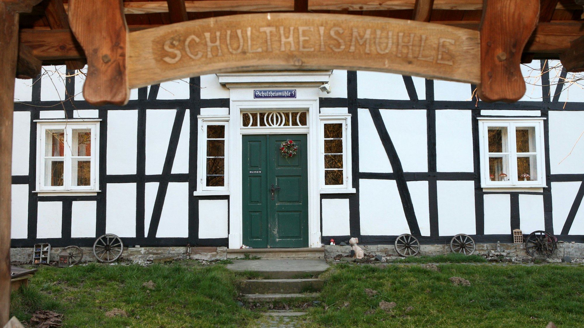 Über dem Zugang zu einem Fachwerkhaus ist ein Holzschild mit der Aufschrift „Schultheismühle“ zu sehen.