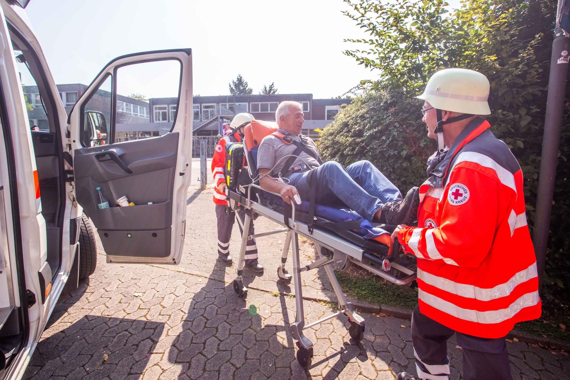 Zwei Helfer des DRK schieben eine Trage mit einem Patienten.