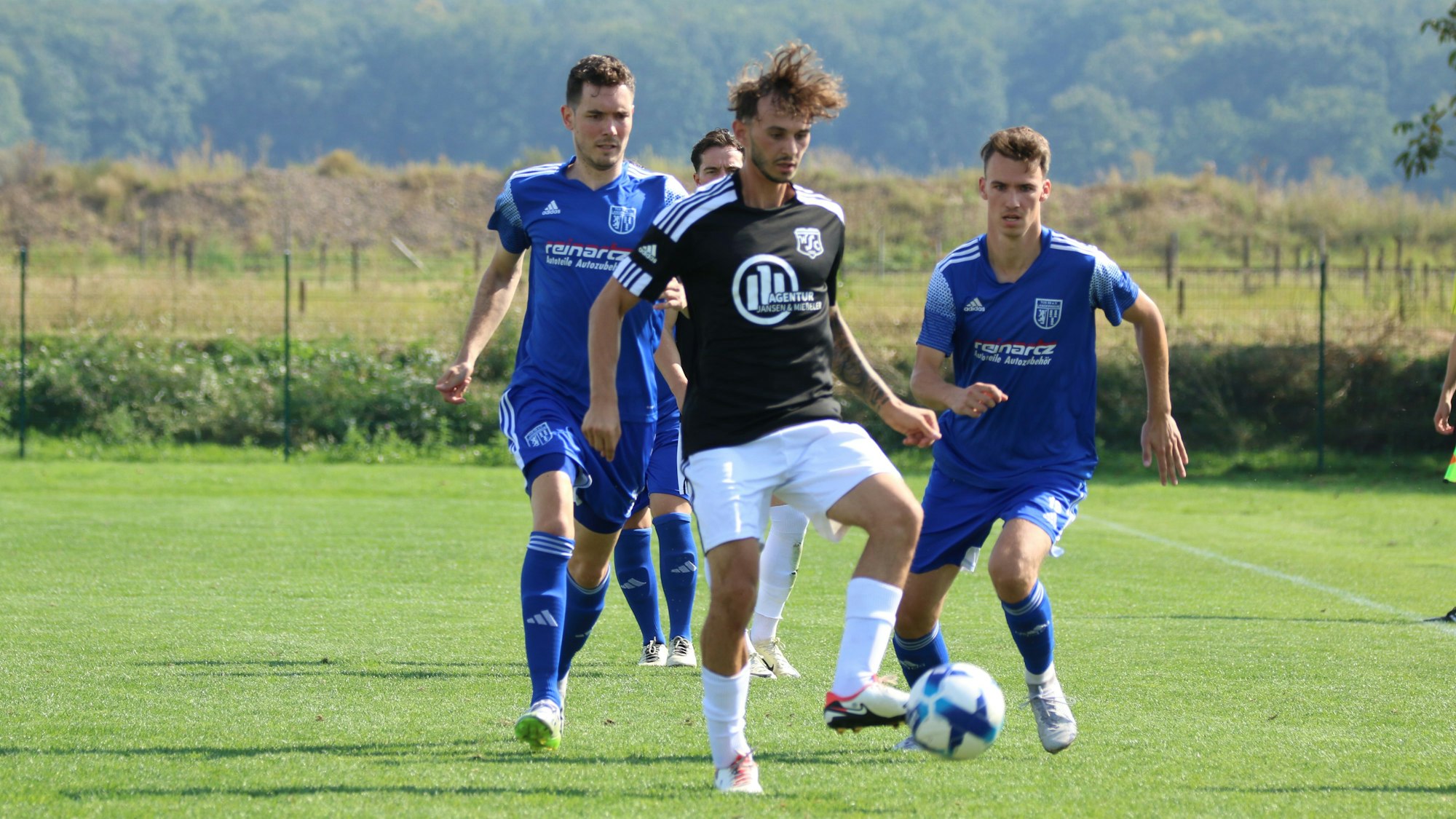 Ein Fußballer passt einen Ball. Seine Haare wehen.