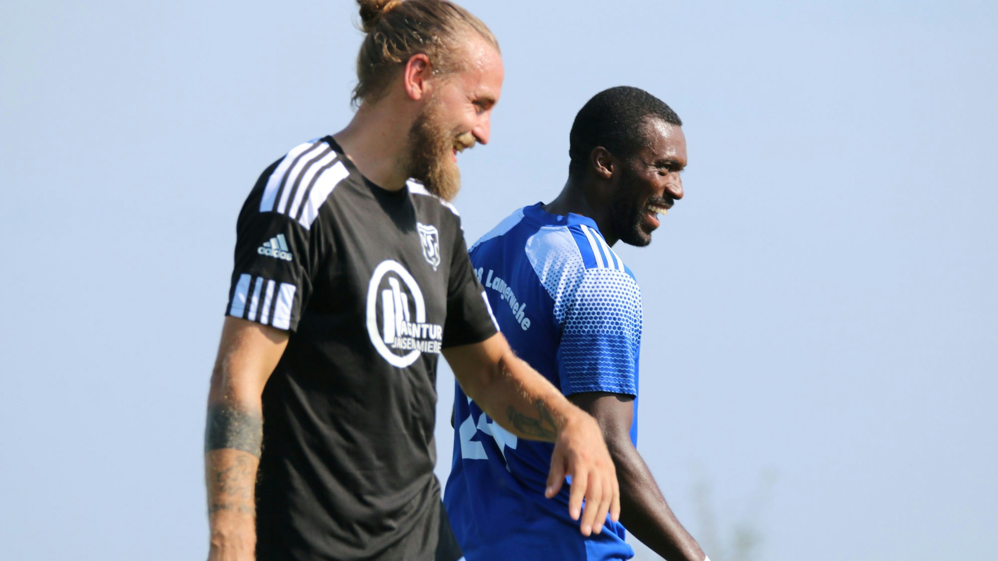 Zwei Gegenspieler lachen miteinander.