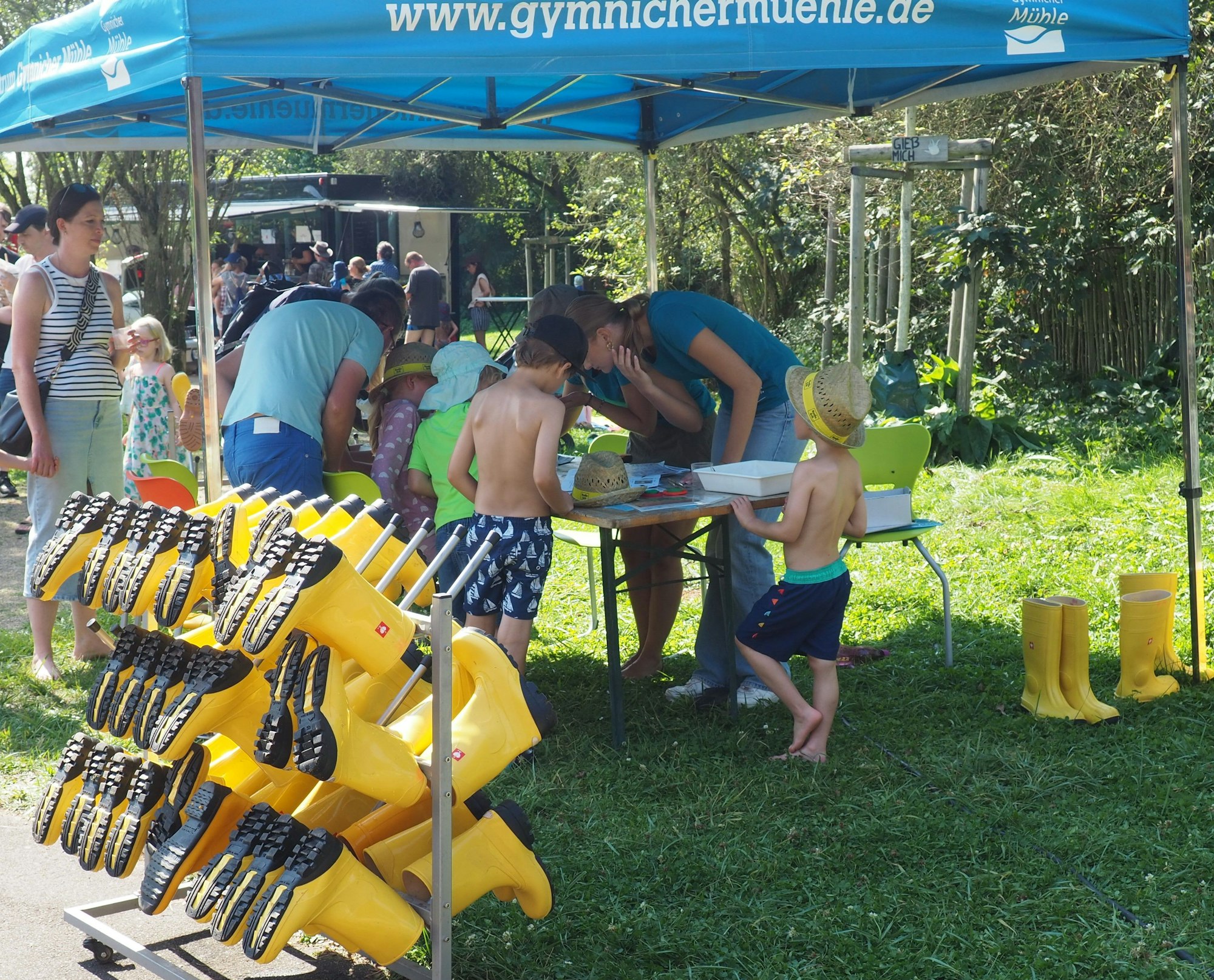 Auf dem Bild ist ein Stand zu sehen, an dem sich Kinder Gummistiefel ausleihen können.