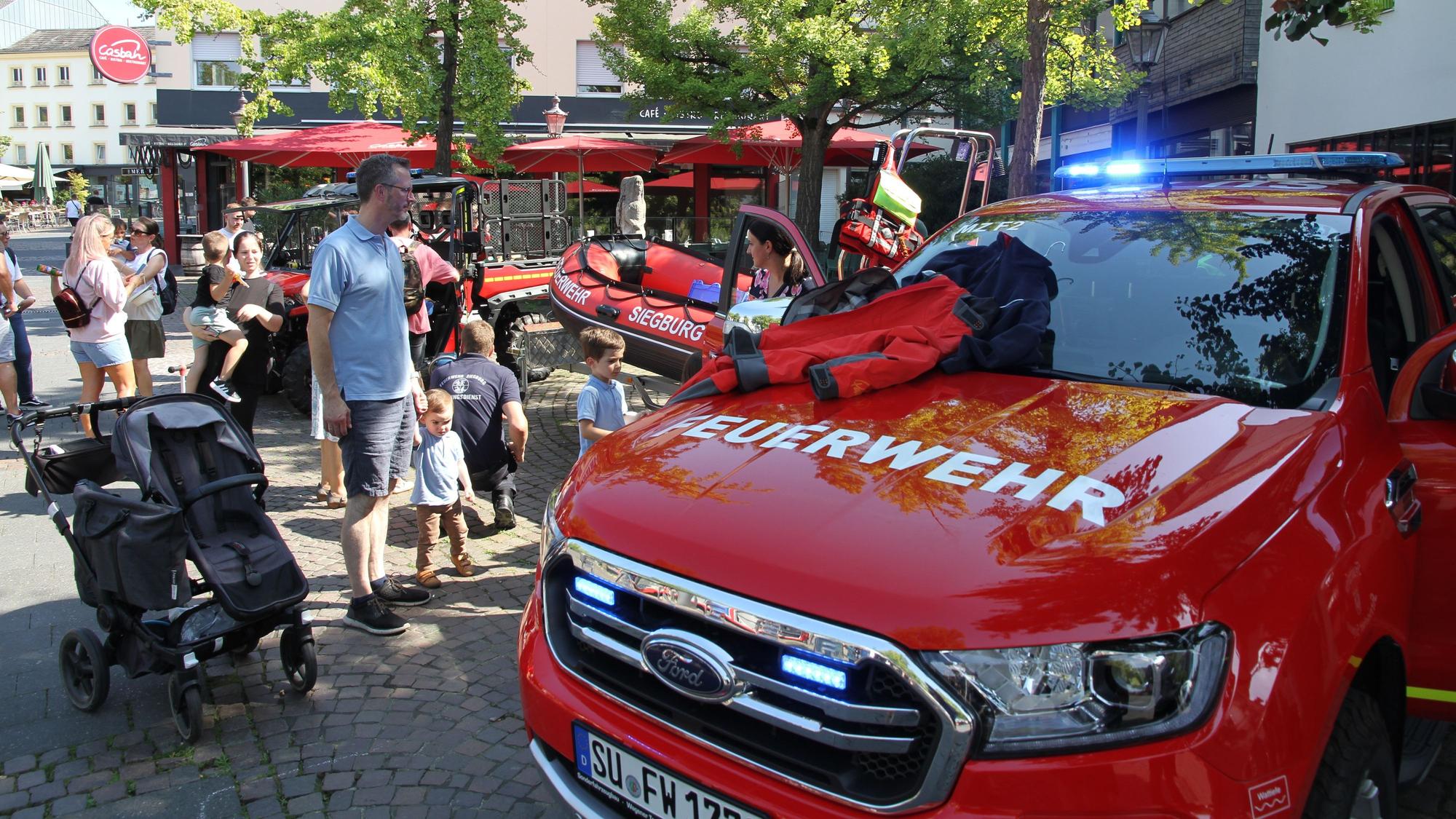 Besucher eines Feuerwehrtags sehen sich Fahrzeuge an.