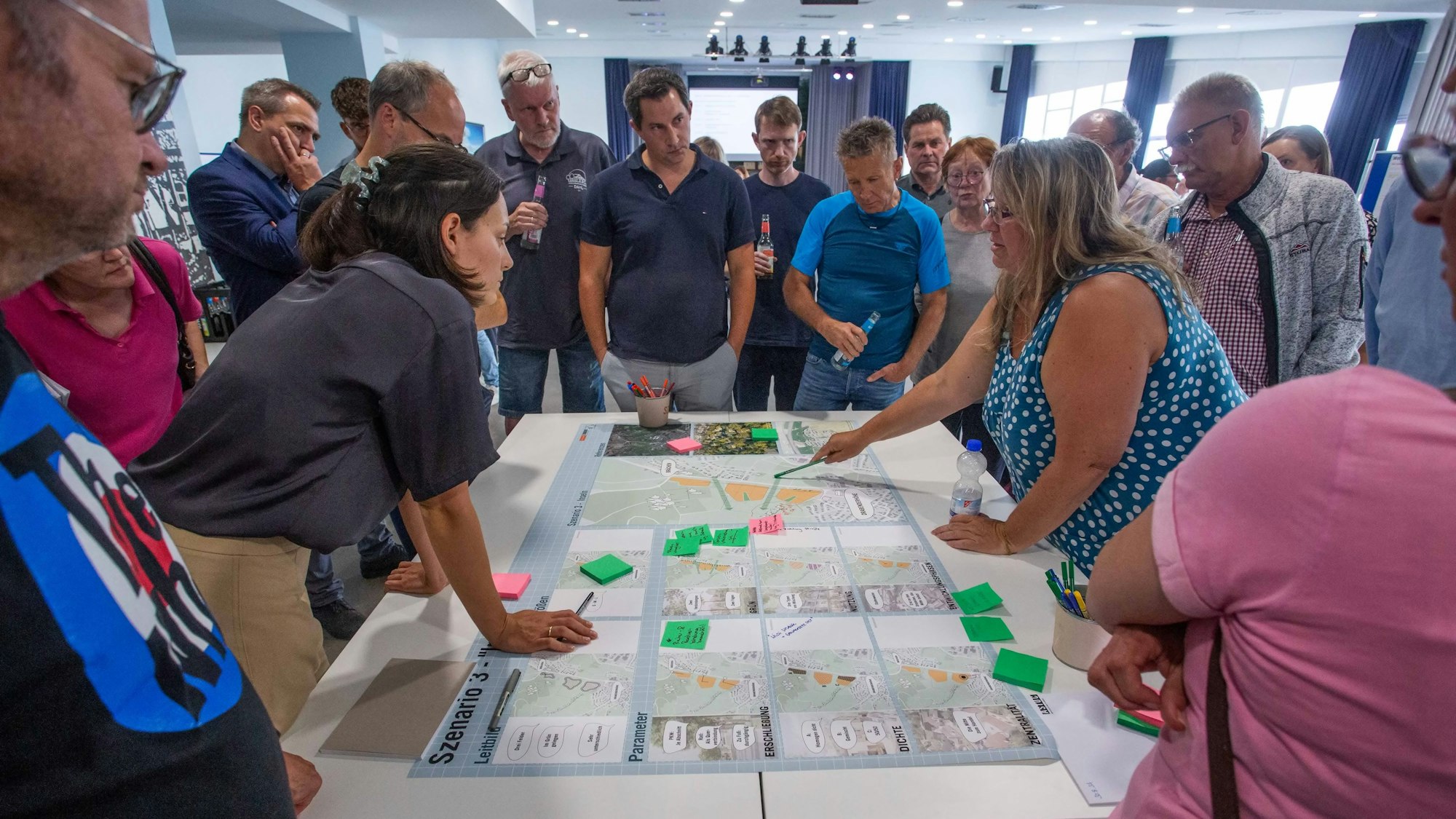Menschen beugen sich über auf einem Tisch ausgebreitete Pläne.