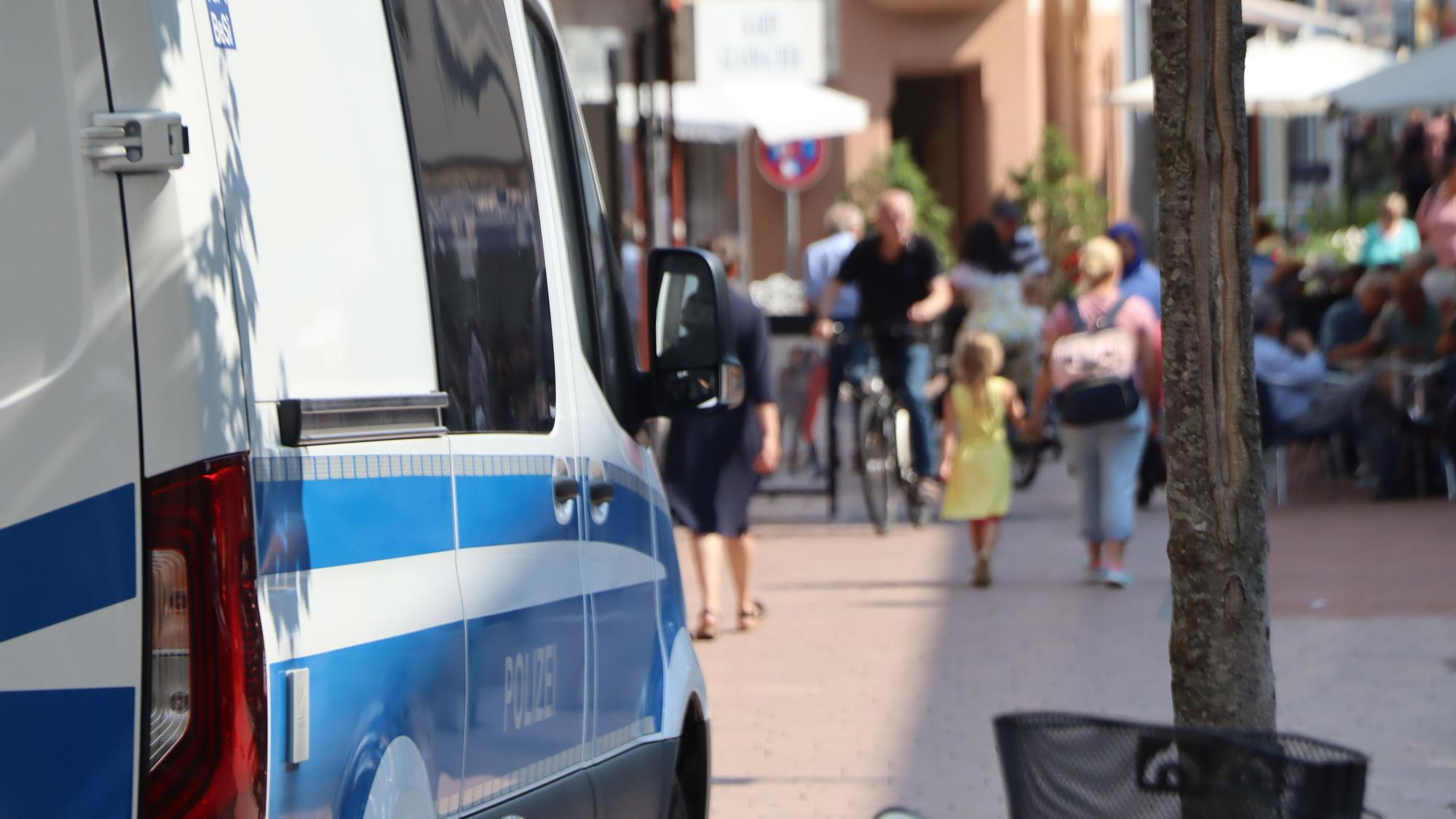 Ein Polizeiauto steht am Rand einer Fußgängerzone.