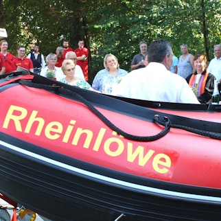 Männer und Frauen neben einem Schlauchboot.