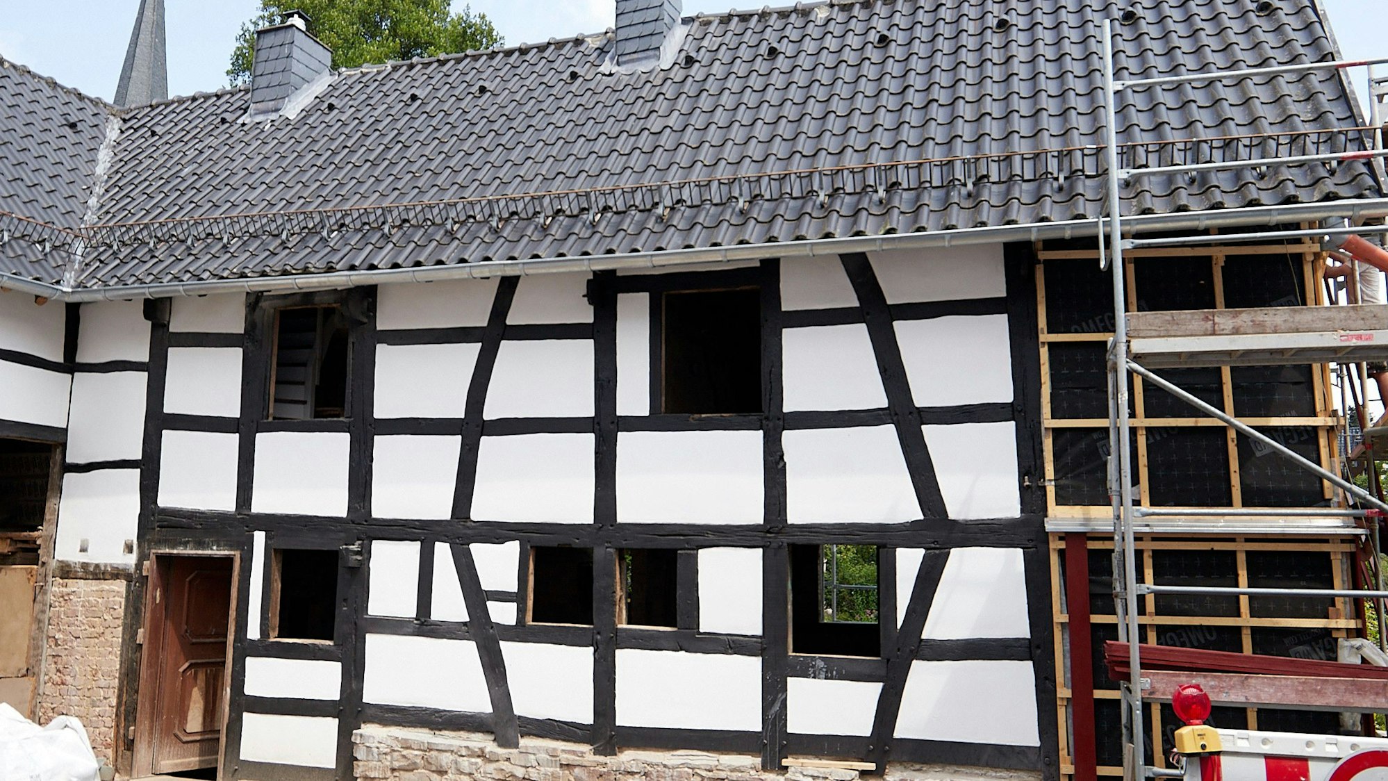 Das Bild zeigt eine Außenansicht des Gebäudes. Während man an vielen Stellen den Fortschritt sieht, steht rechts ein Gerüst.