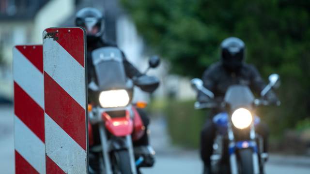 Motorradfahrer fahren an Warnbaken vorbei.