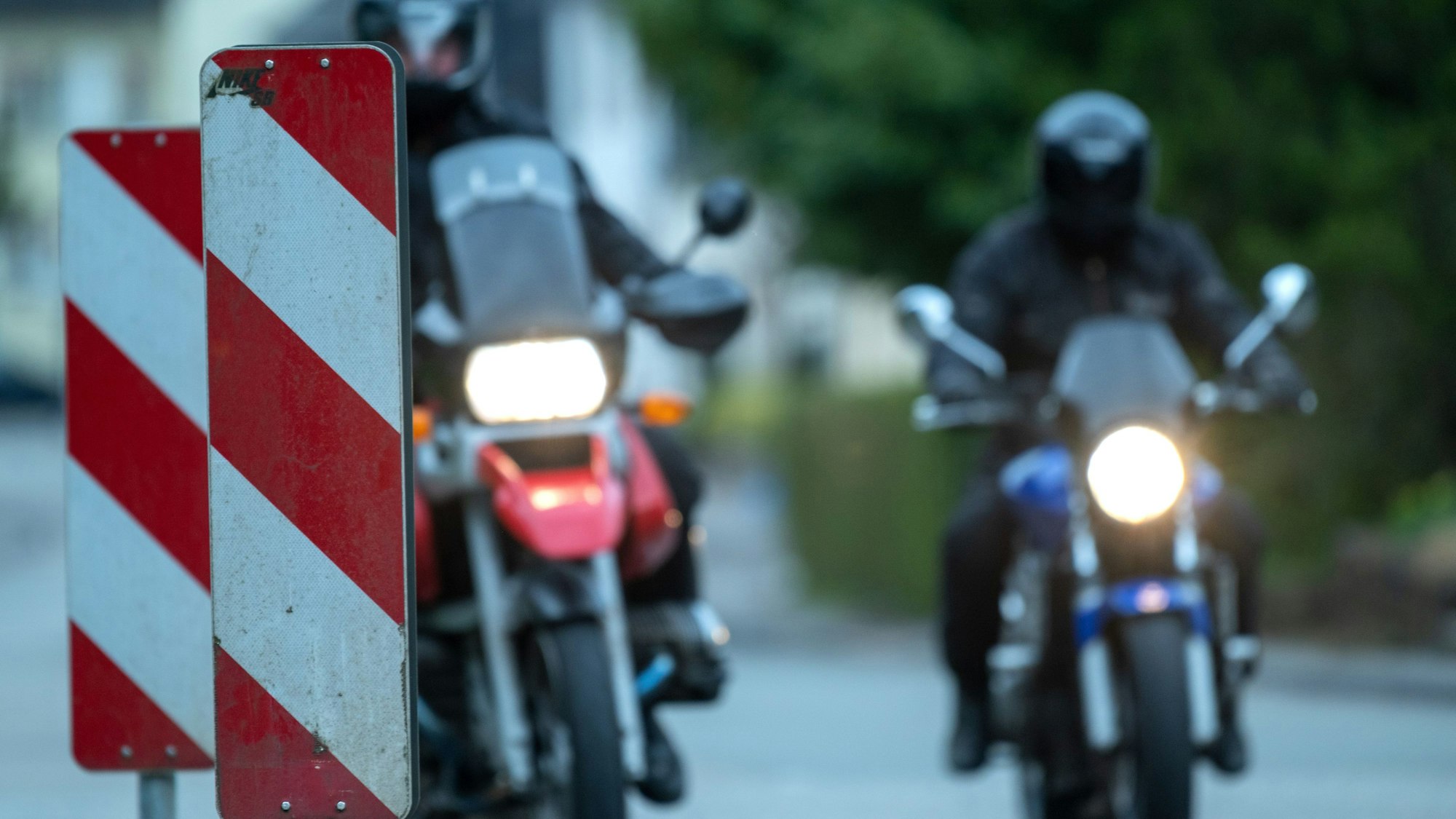 Motorradfahrer fahren an Warnbaken vorbei.