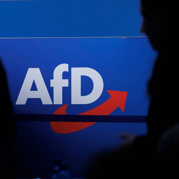 Delegierte gehen vor dem Parteilogo bei dem AfD-Bundesparteitag in Magdeburg.