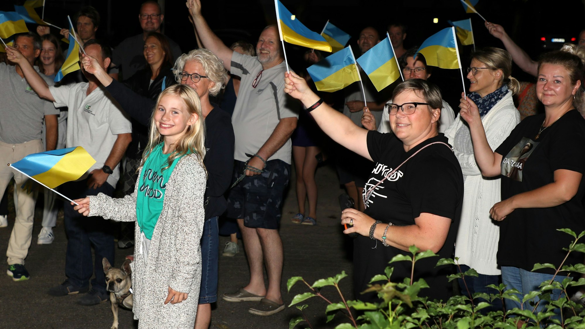 Menschen schwenken ukrainische Fähnchen in der Nacht.