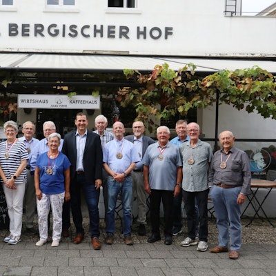 Eine Gruppe von Männer und Frauen vor der Terrasse eines Lokals.