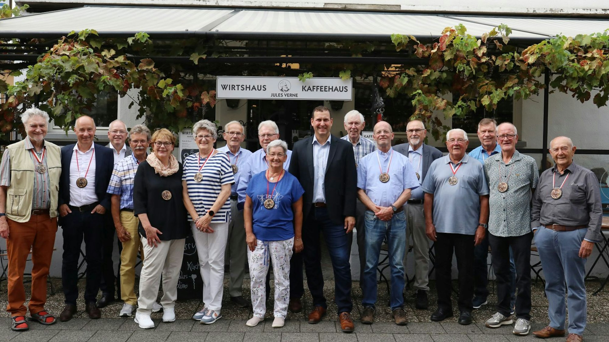 Eine Gruppe von Männer und Frauen vor der Terrasse eines Lokals.