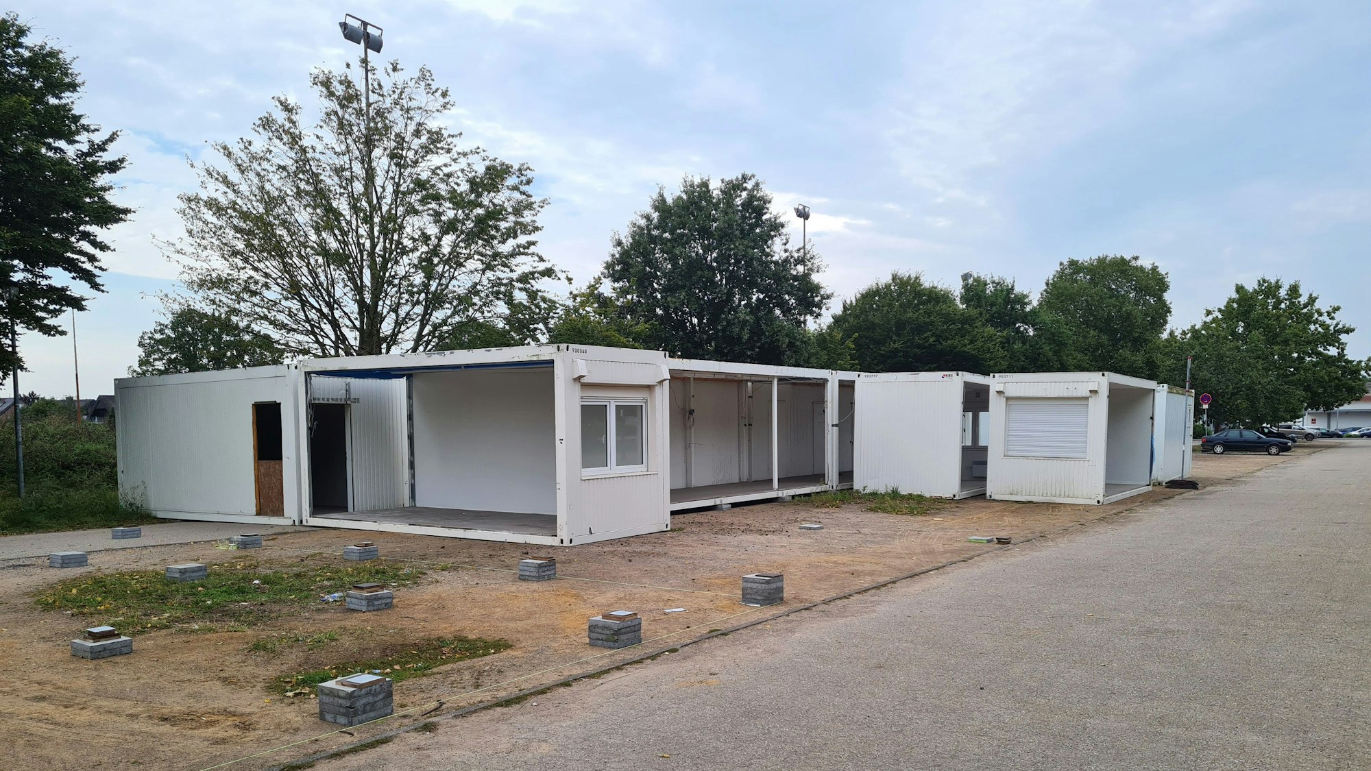 Weiße Container stehen an einer Straße.