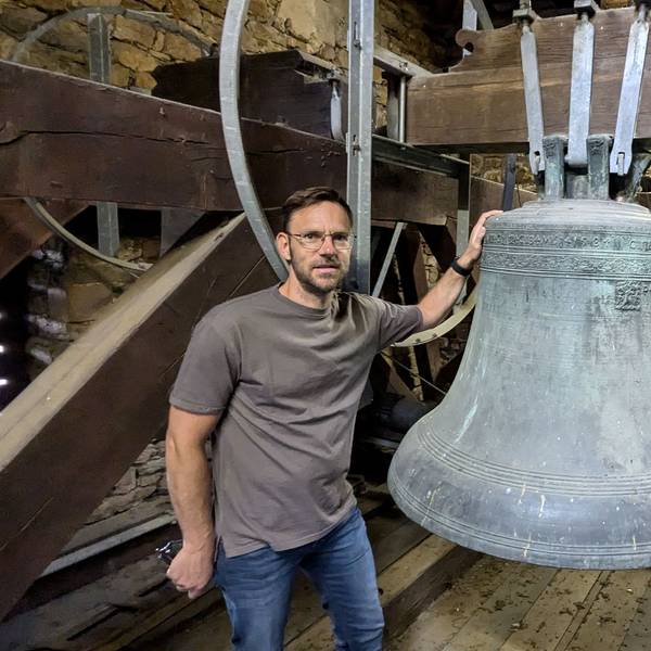 Ortsbürgermeister und Kirchenvorstand Björn Wassong steht in der Kirche in Mechernich-Weyer an der Cyriakus-Glocke von 1584.