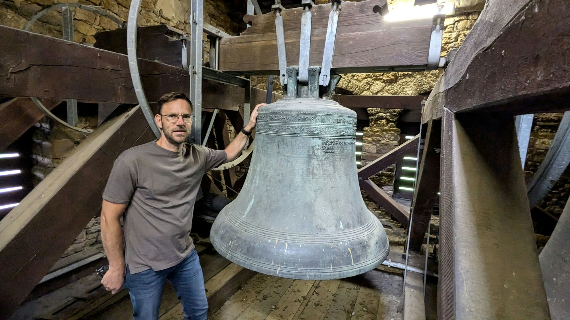 Ortsbürgermeister und Kirchenvorstand Björn Wassong steht in der Kirche in Mechernich-Weyer an der Cyriakus-Glocke von 1584.