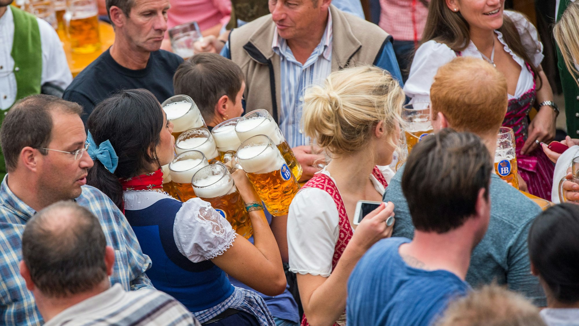 Eine Kellnerin trägt auf dem Münchner Oktoberfest auf der Theresienwiese in München (Bayern) im Hofbräuzelt zehn Maß Bier zu einem Tisch.