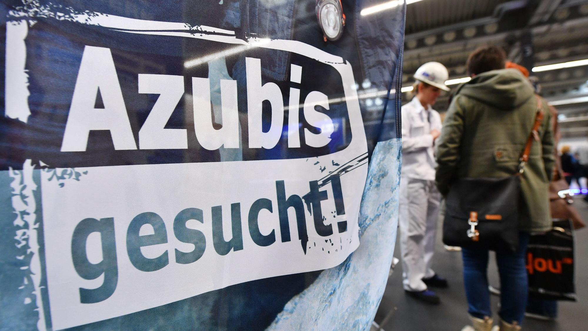 Ein Banner mit der Aufschrift „Azubis gesucht“ hängt in einer Werkhalle.