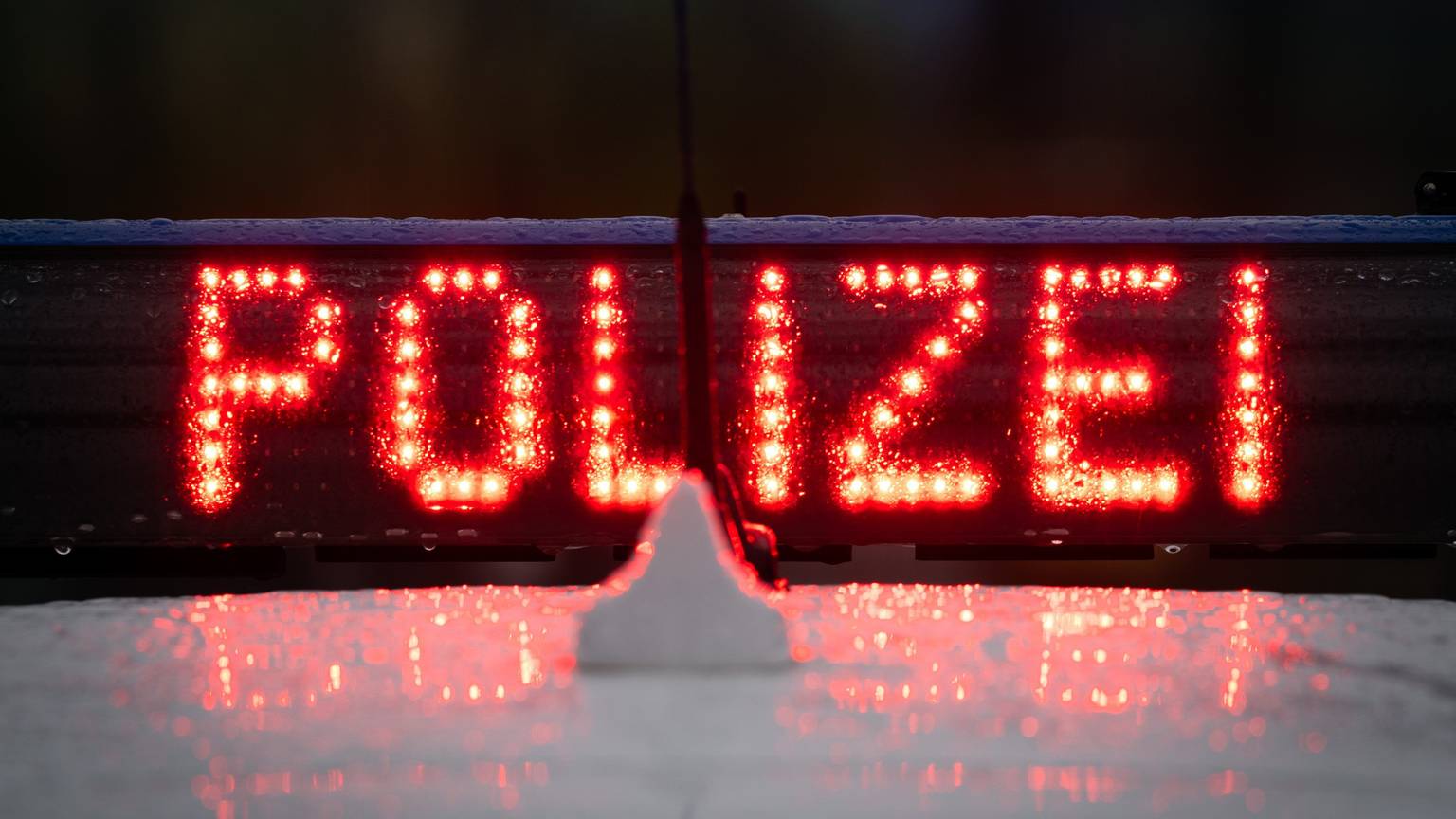 Der Schriftzug „Polizei“ leuchtet in Rot auf einem Autodach.