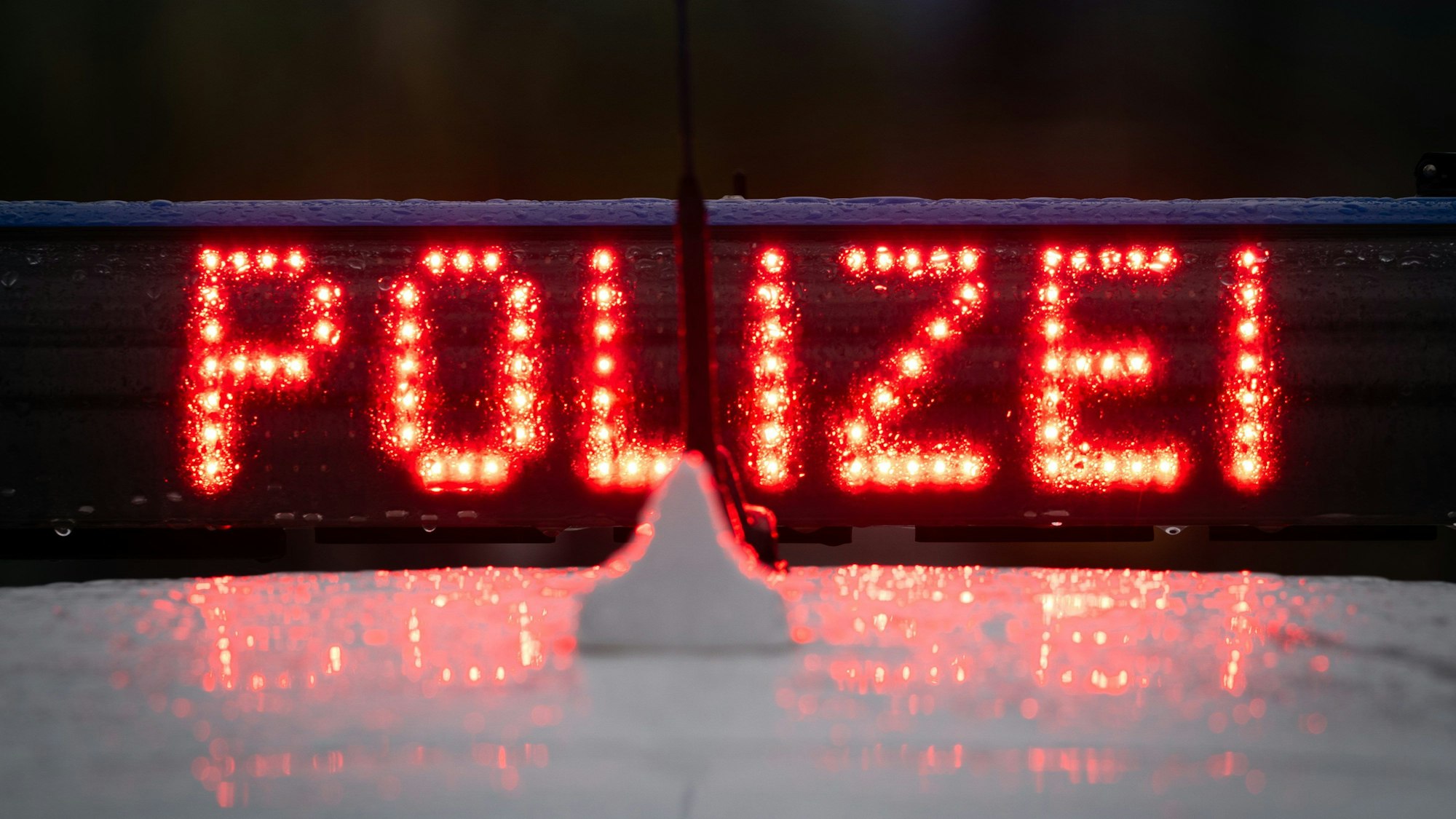 Der Schriftzug „Polizei“ leuchtet in Rot auf einem Autodach.