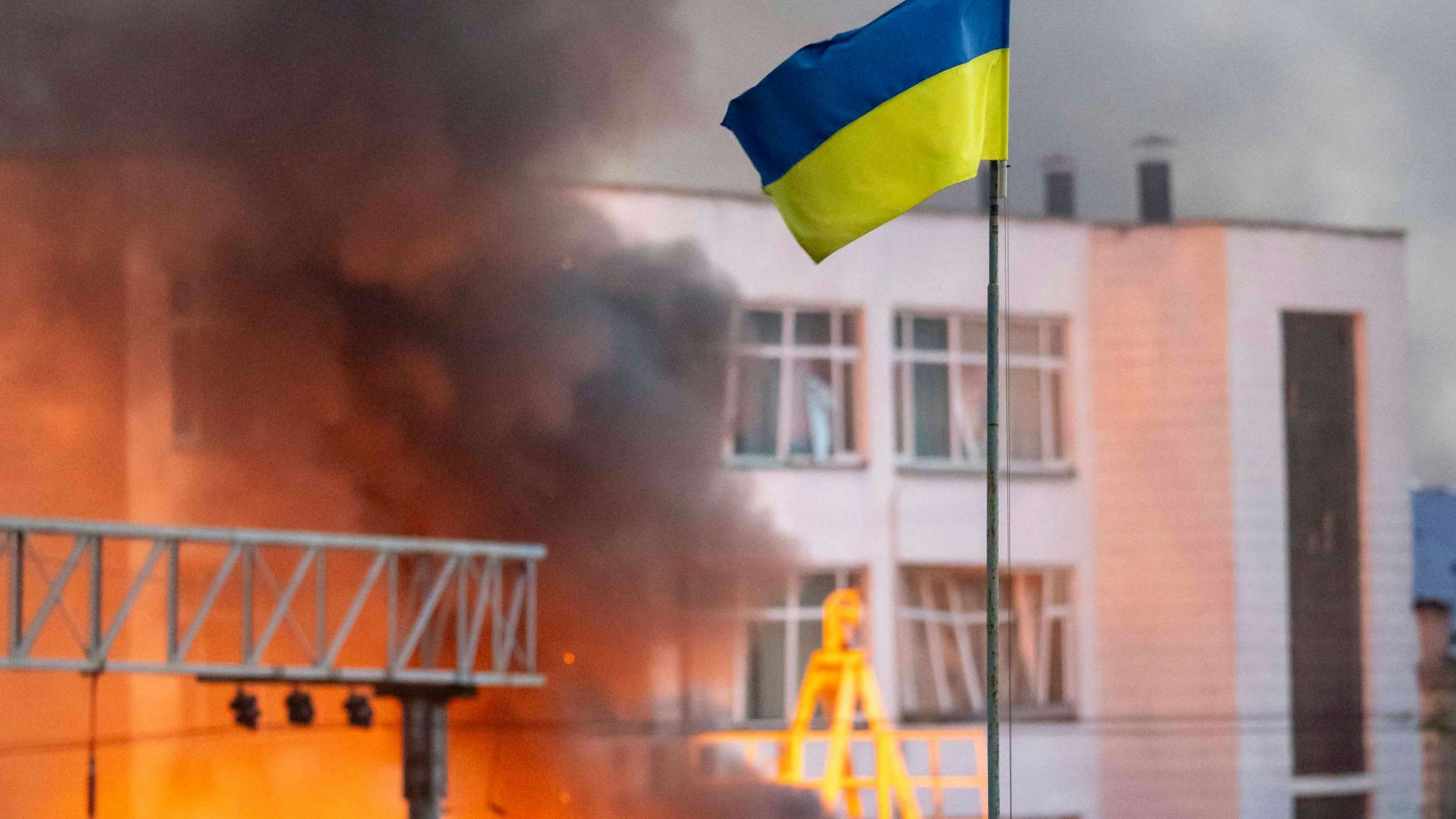 02.09.2024, Ukraine, Kiew: Die ukrainische Flagge weht über dem dichten Rauch, der von einem Feuer nach einem russischen Raketenangriff aufsteigt. Foto: Andreas Stroh/ZUMA Press Wire/dpa +++ dpa-Bildfunk +++