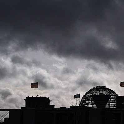 Berlin: Wolken sind über der Kuppel vom Reichstag zu sehen, auf dem Deutschlandfahnen wehen.