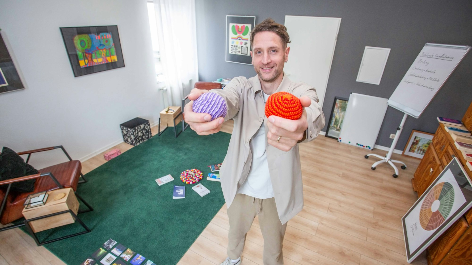 Ein Mann hält zwei Bälle in die Kamera.