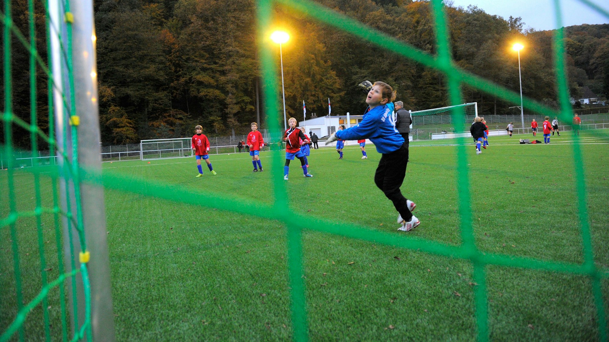 Eine Jungenmannschaft spielt auf einem Kunstrasenplatz Fußball.