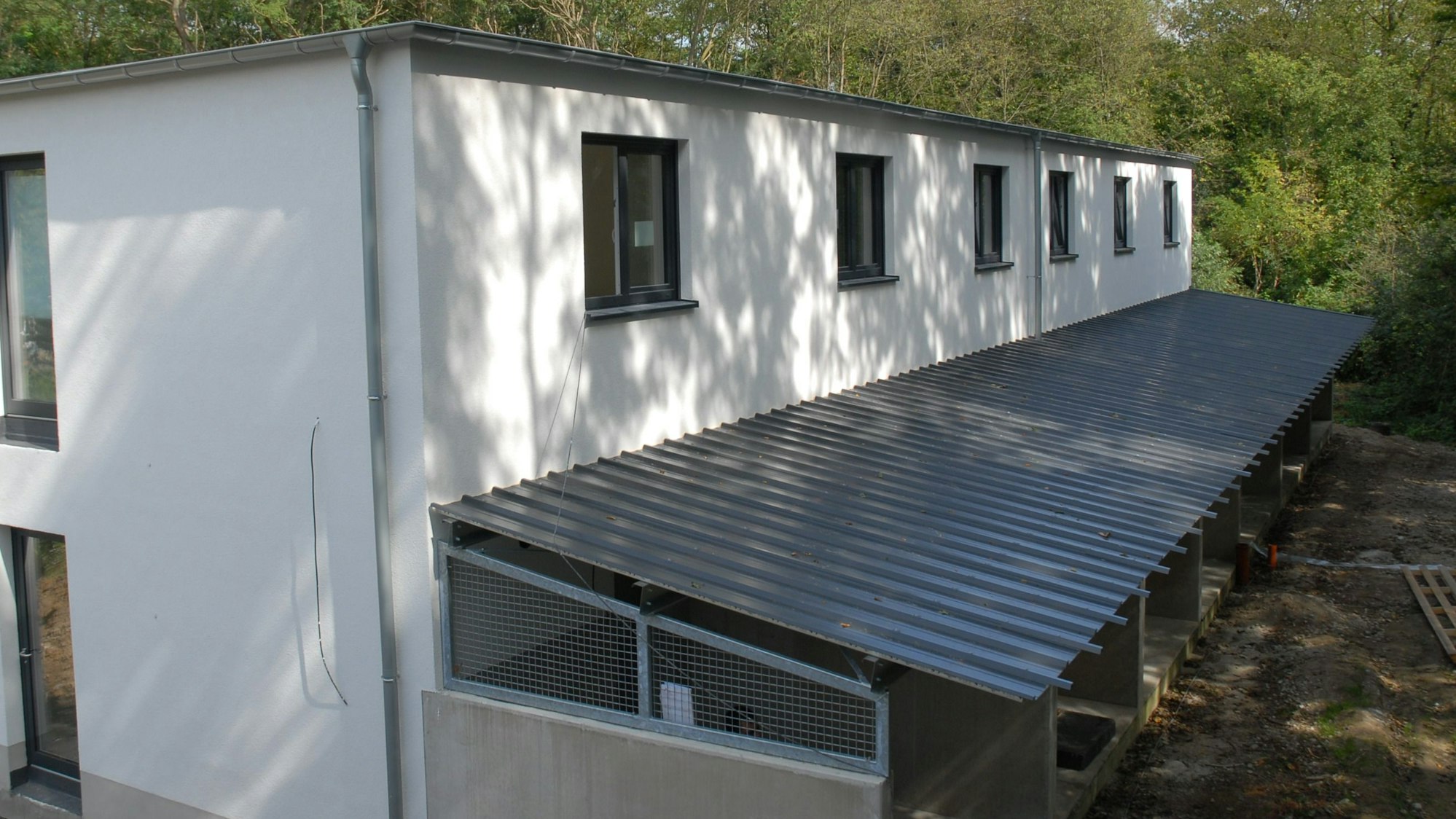 Zu sehen ist ein Gebäude mit überdachten Hundeausläufen.