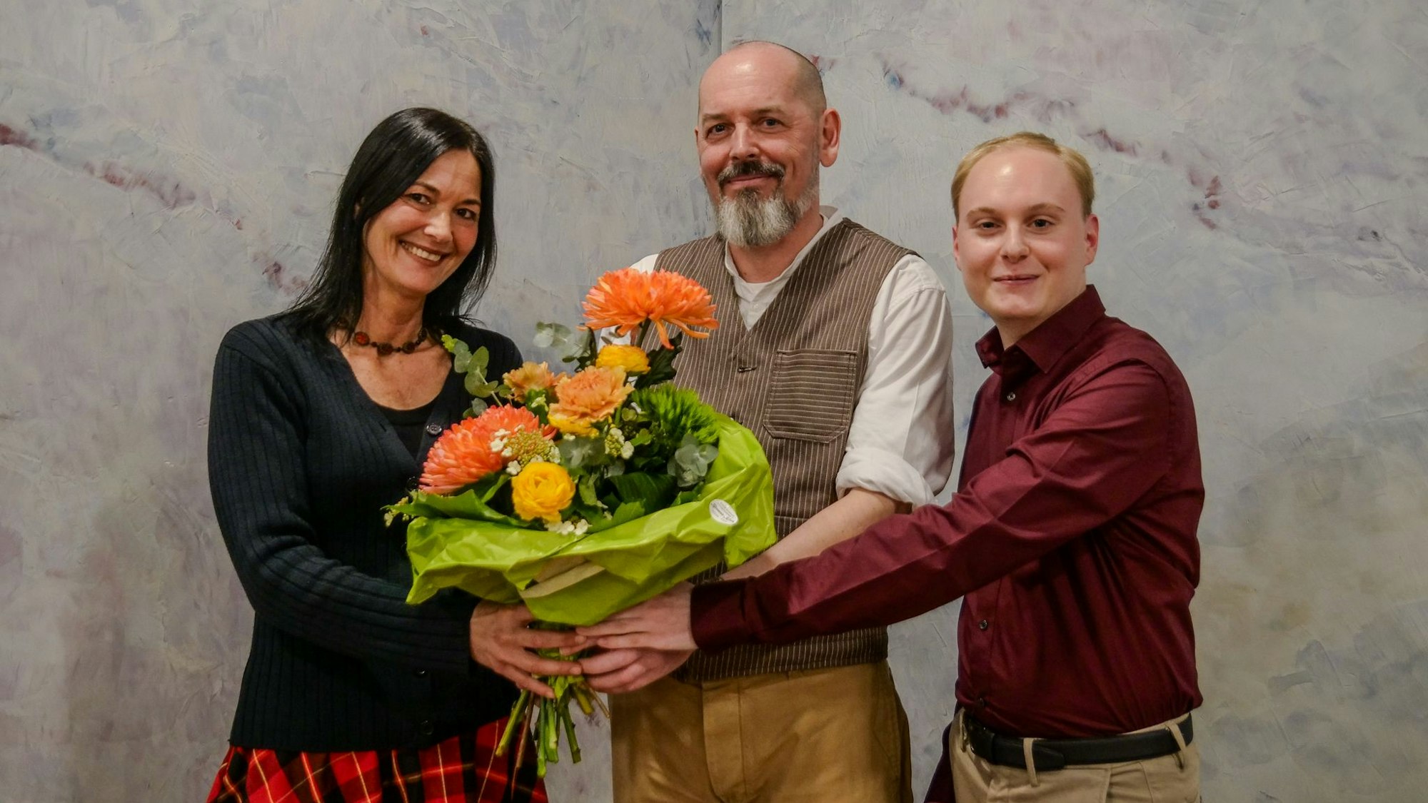 Links und rechts von Thommy Mewes übergeben Tina Conrady und Christian Schubert ihrem Kandidaten einen Strauß Blumen.