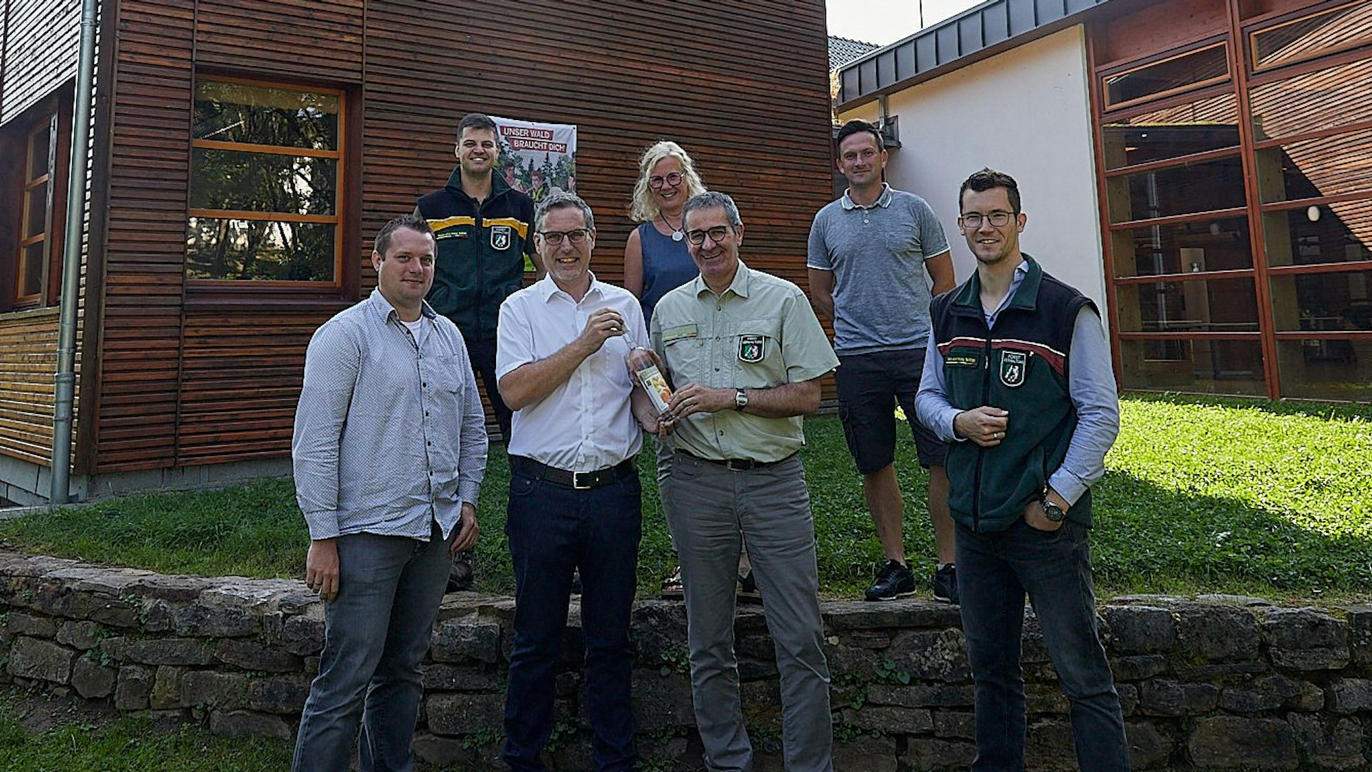 Im Kreis von Mitarbeitern des Regionalforstamtes begrüßen Bürgermeister Norbert Crump und Alexander Mauel den Leiter Christoph Böltz zur Wiederkehr der Einrichtung mit einem hochprozentigen Willkommensgeschenk.