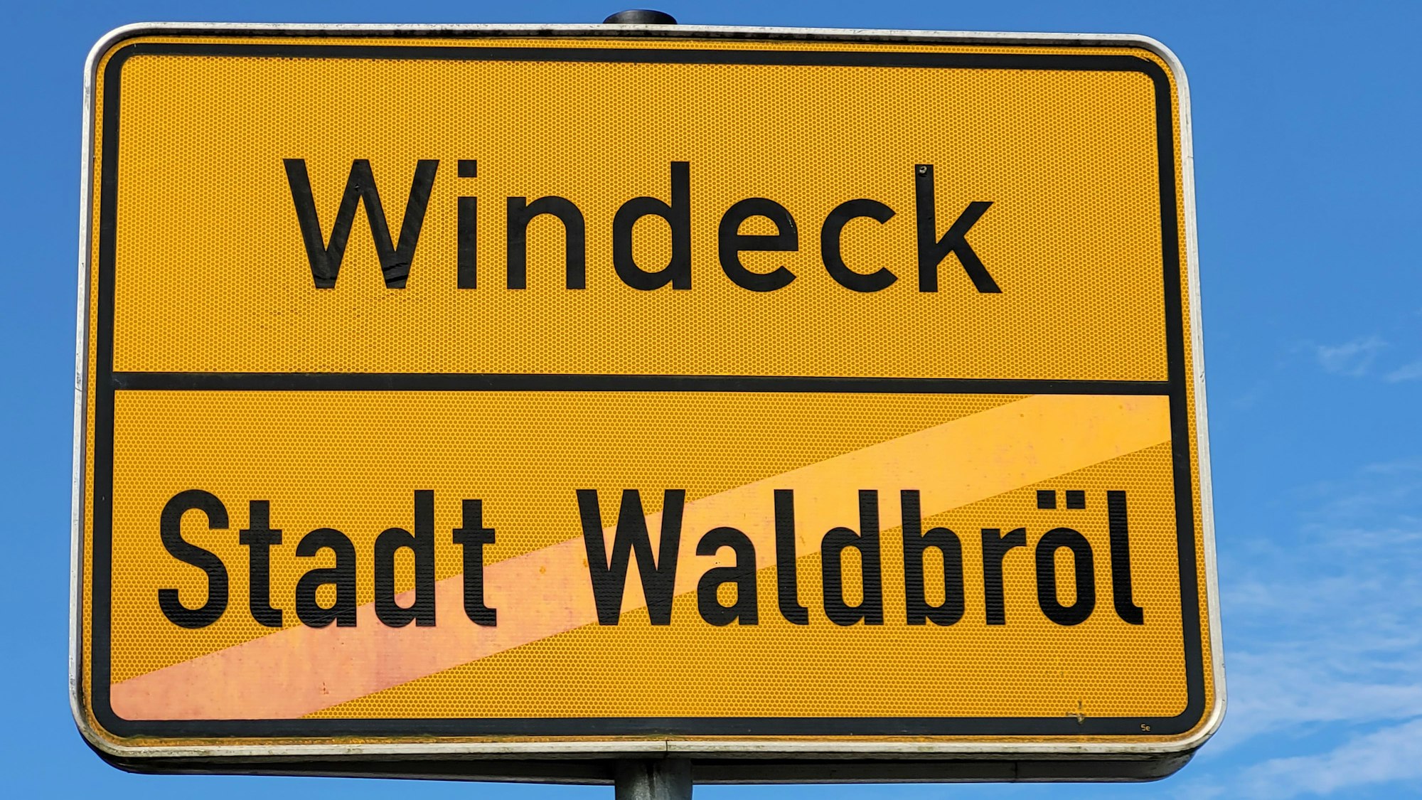 Auf diesem als Ortsausgangsschild gedachten Verkehrszeichen ist die Stadt Waldbröl heute nicht mehr durchgestrichen, dafür aber eng vereint mit ihrer Nachbargemeinde Windeck.