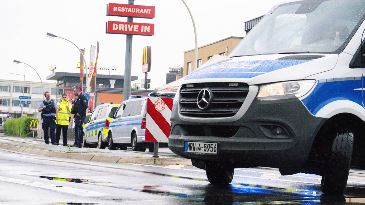 Einsatzkräfte der Polizei stehen mit Einsatzwagen auf einer Straße.