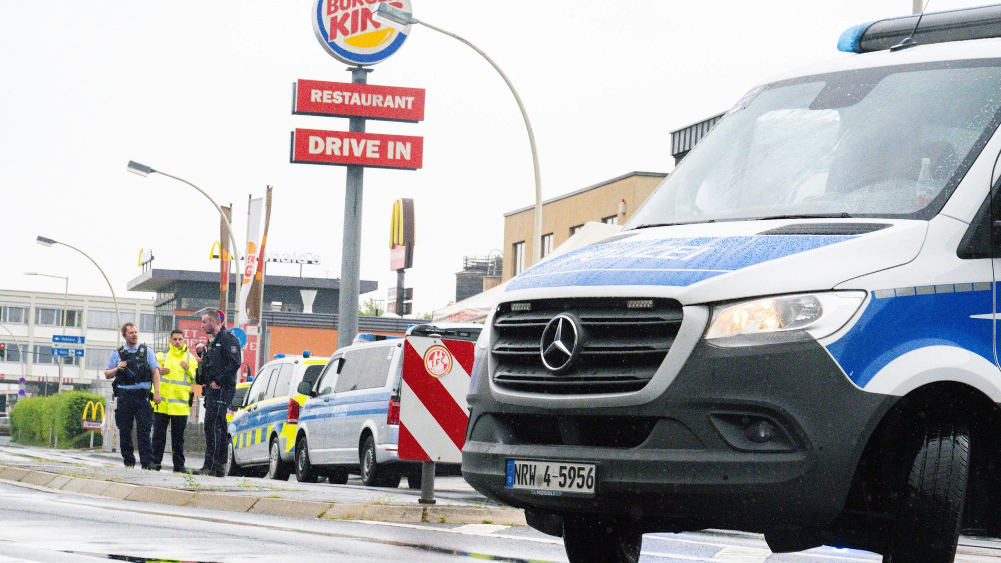 Einsatzkräfte der Polizei stehen mit Einsatzwagen auf einer Straße.