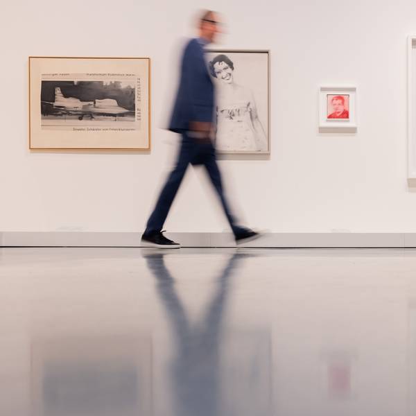 Bilder des Künstlers Gerhard Richter hängen an einer Wand, an der ein Mann vorbeigeht.