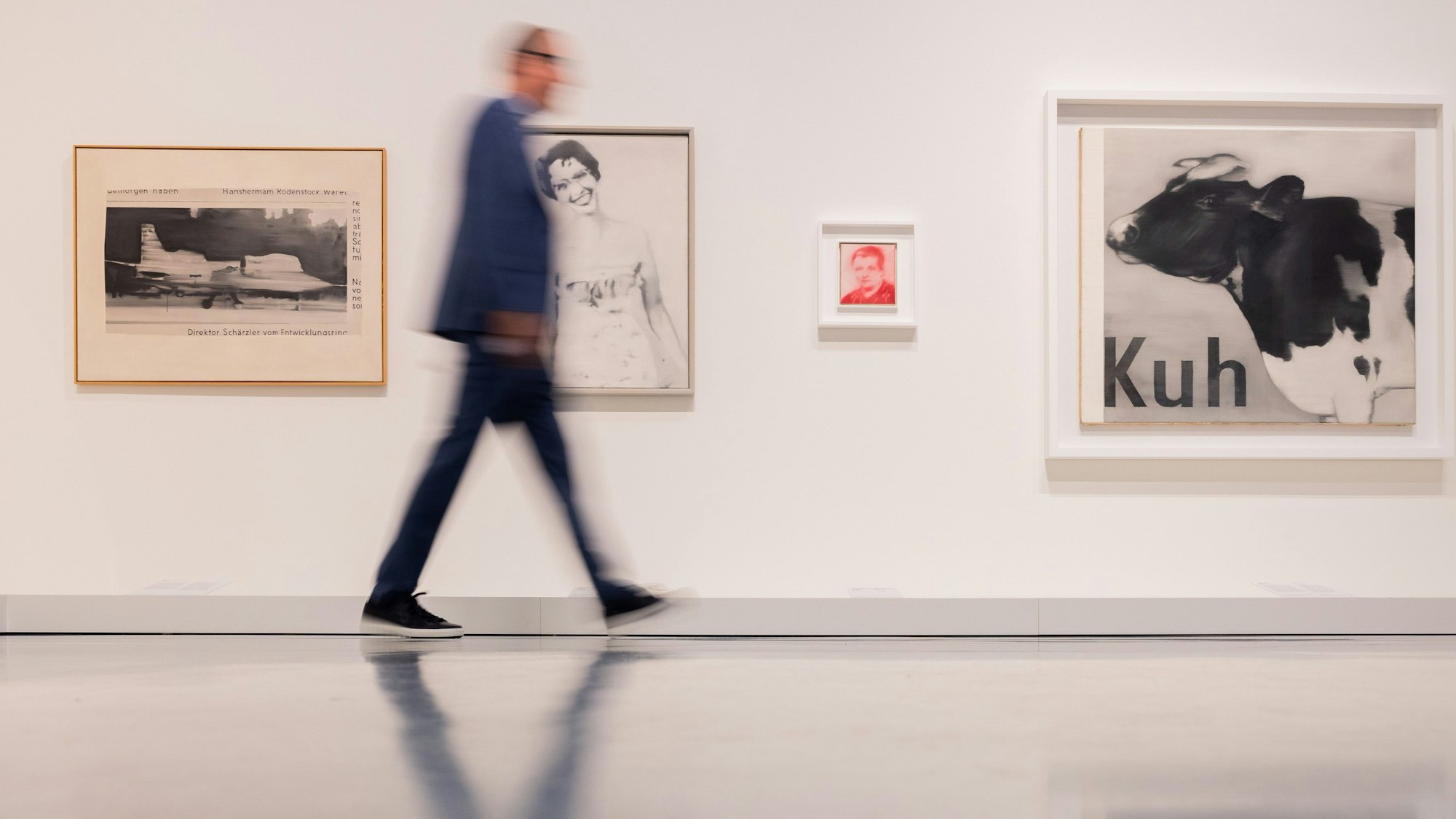 Bilder des Künstlers Gerhard Richter hängen an einer Wand, an der ein Mann vorbeigeht.