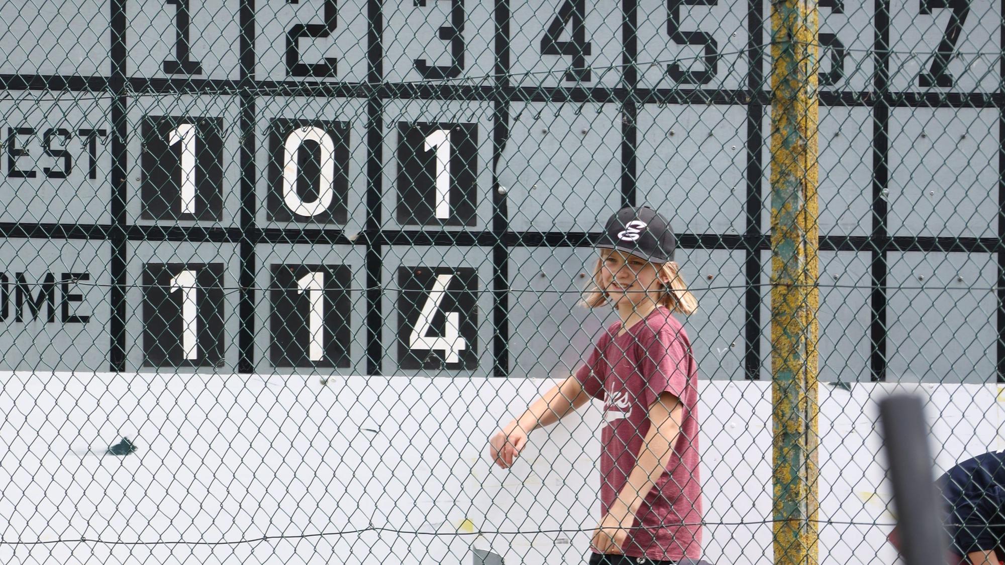 Ein Kind steht an einer Baseball-Anzeigetafel.