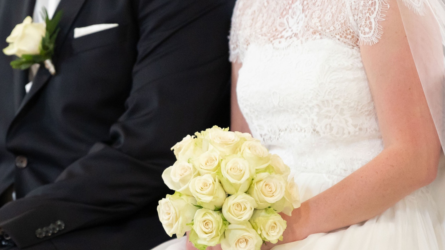 Ein Brautpaar sitzt während ihrer Trauung in der Kirche.