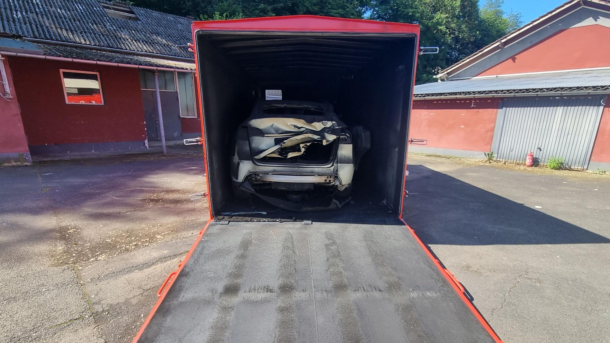 Ein Schrottauto steht in einem Container.