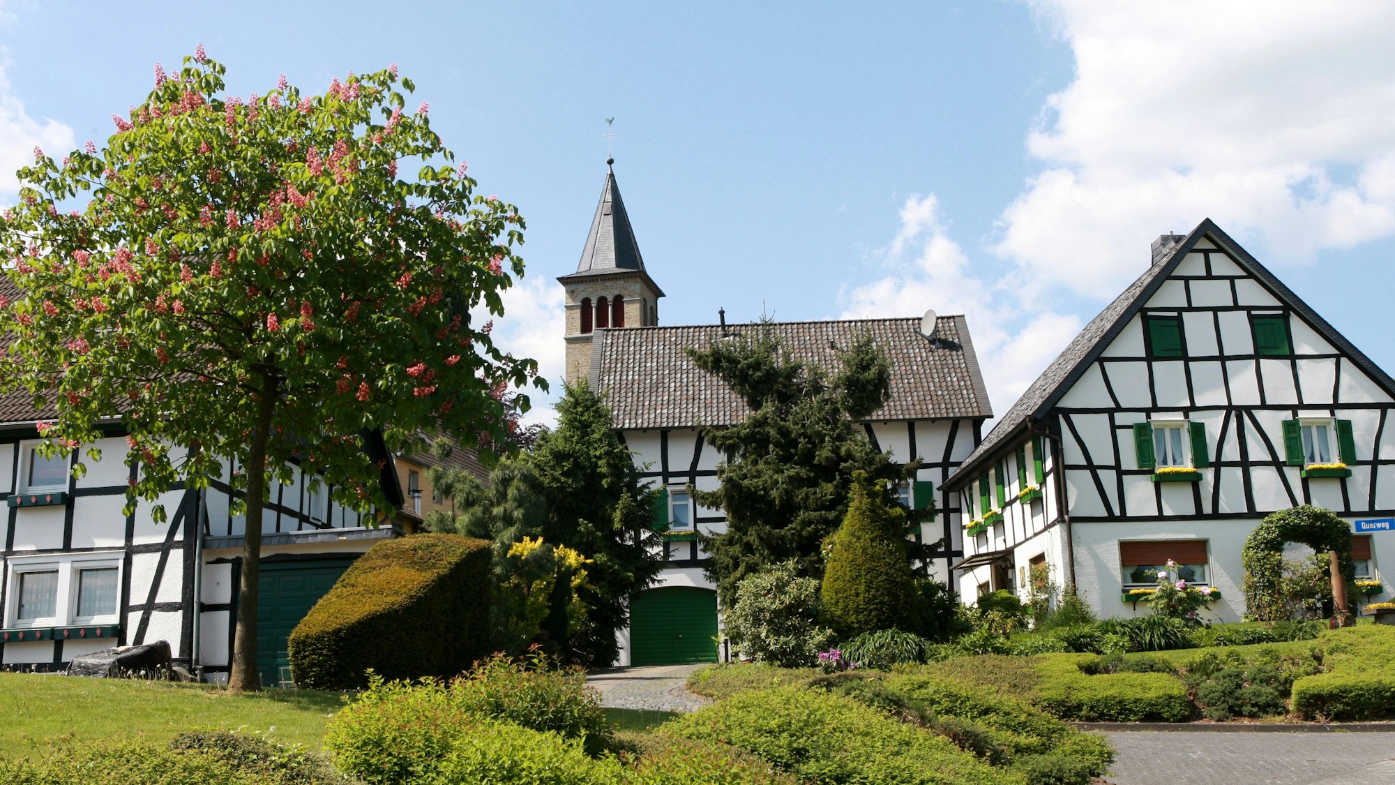 Hinter Fachwerkhäusern von Neunkirchen-Seelscheid ist die evangelische Kirche des Ortes zu sehen.