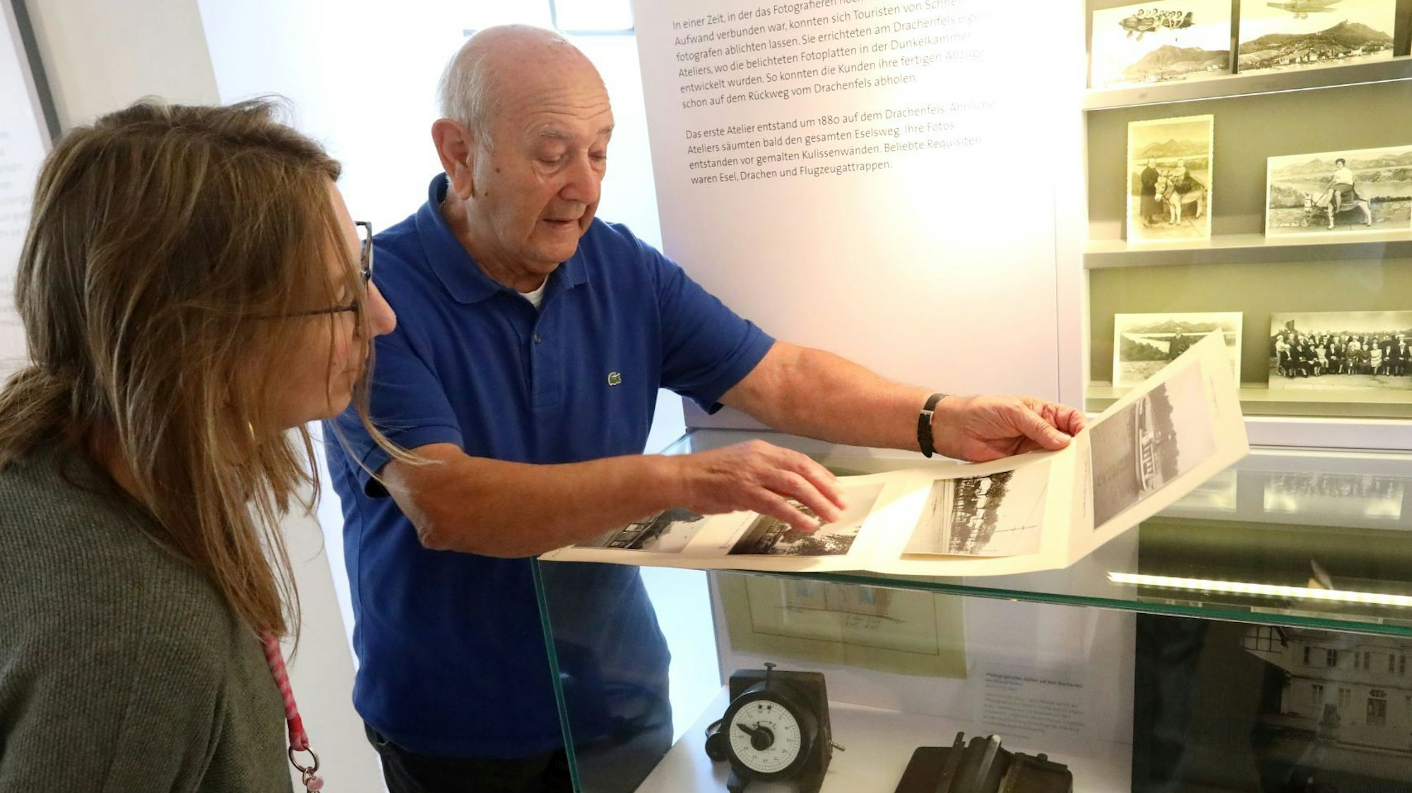 Eine Frau und ein Mann schauen historische Fotoaufnahmen an.