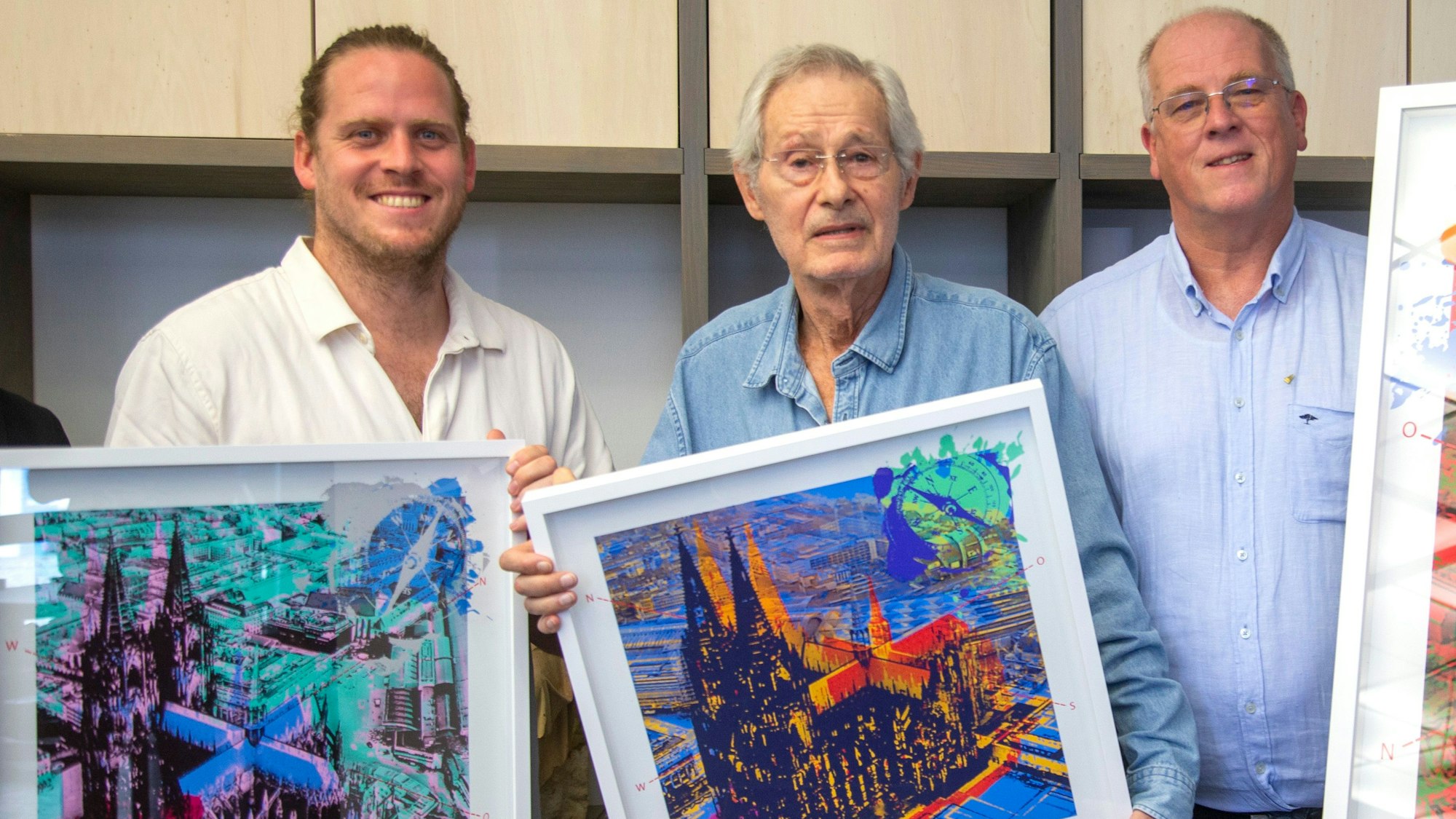 Grafiker Hans-Jürgen Kuhl (M.) präsentiert gemeinsam mit Lukas Boecker (l.) und Robert Boecker die limitierte Domgrafik, die der Zentral-Dombau-Verein zu Gunsten des Erhalts der Kathedrale vertreibt.