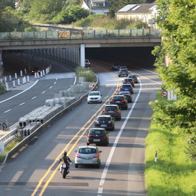 Eine vierspurige Straße, auf der die linke Hälfte für den Verkehr gesperrt ist. Im Hintergrund fahren Autos in den Tunnel Oberkassel