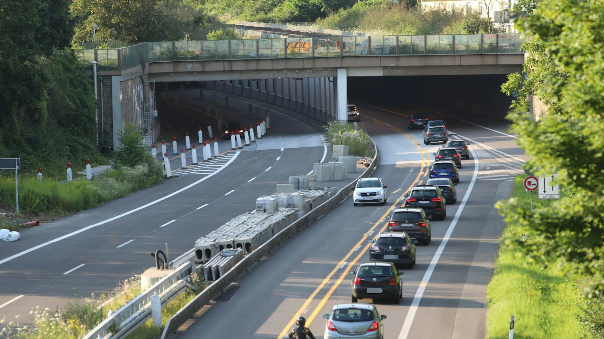 Eine vierspurige Straße, auf der die linke Hälfte für den Verkehr gesperrt ist. Im Hintergrund fahren Autos in den Tunnel Oberkassel
