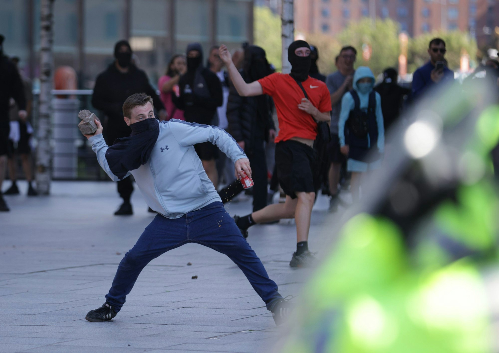 03.08.2024, Großbritannien, Liverpool: Ein Mann wirft einen Ziegelstein während einer Demonstration nach den Messerangriffen