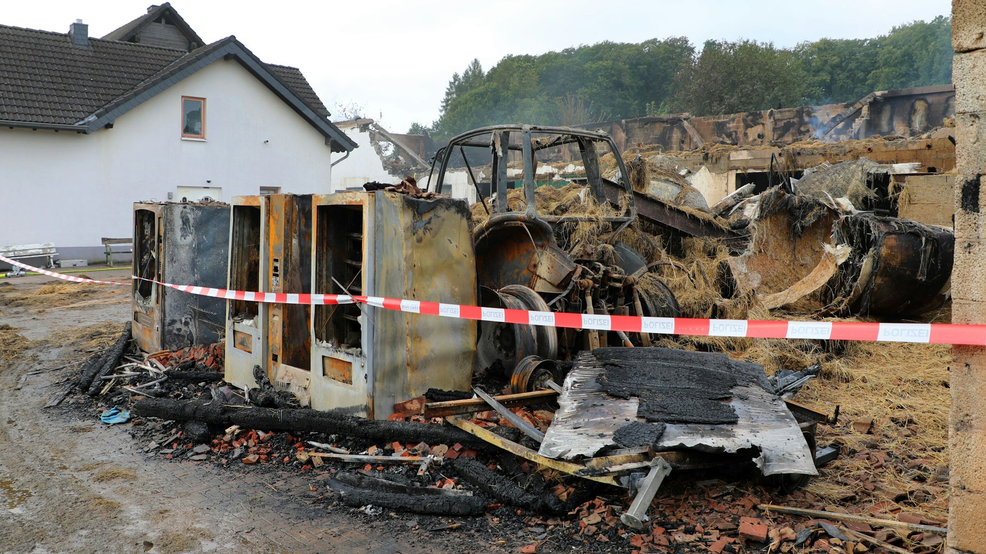 Blick auf einen abgebrannten Bauernhof, von dem allein noch das Wohngebäude steht.