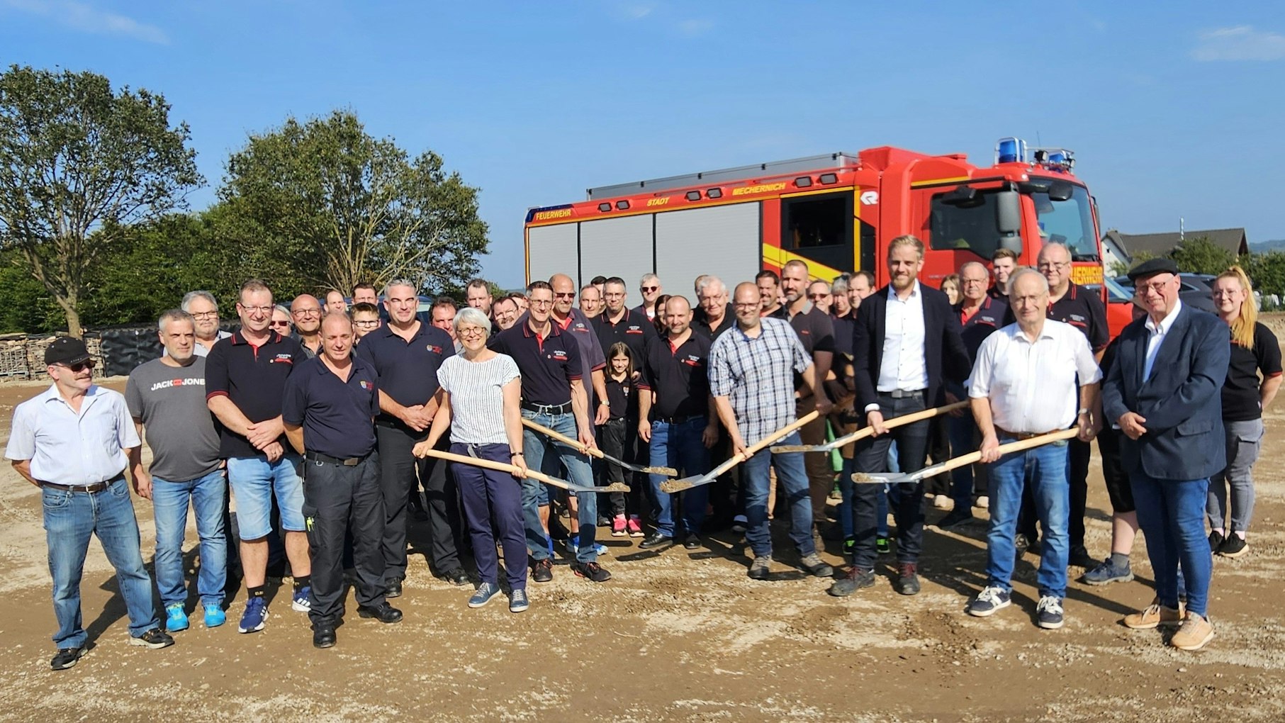 Vertreter von Stadt, Feuerwehr, der Baufirma und des Planungsbüros stehen vor einem Feuerwehrfahrzeug.