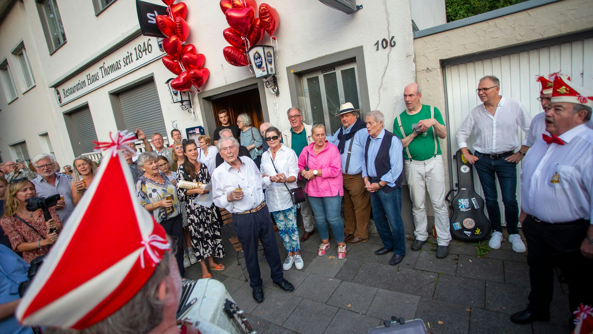 Ein Ständchen für den Jubilar: Der Chor der Roten Funken singt für Ludwig Sebus (MItte, weißes Hemd) vor der Veedelskneipe „Haus Thomas“ auf der Rochusstraße in Bickendorf. Mit Familie und Freunden feierte er seinen 99. Geburtstag.