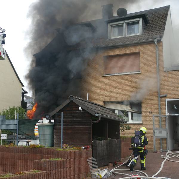 Eine Rauchsäule steigt vor einem Haus auf.